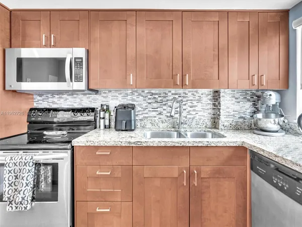 a kitchen with granite countertop stainless steel appliances a stove a microwave and sink