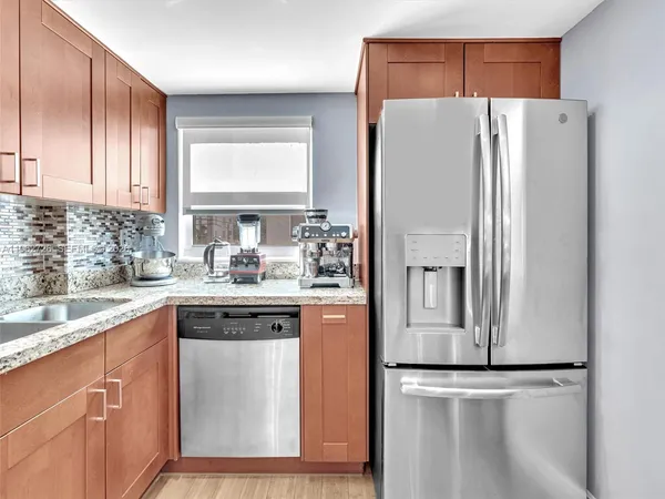 a white kitchen with stainless steel appliances granite countertop a refrigerator and a sink