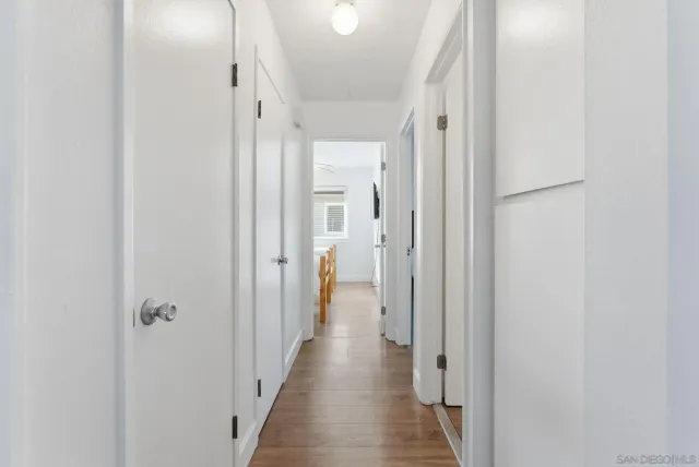 a view of a hallway with wooden floor and a bathroom