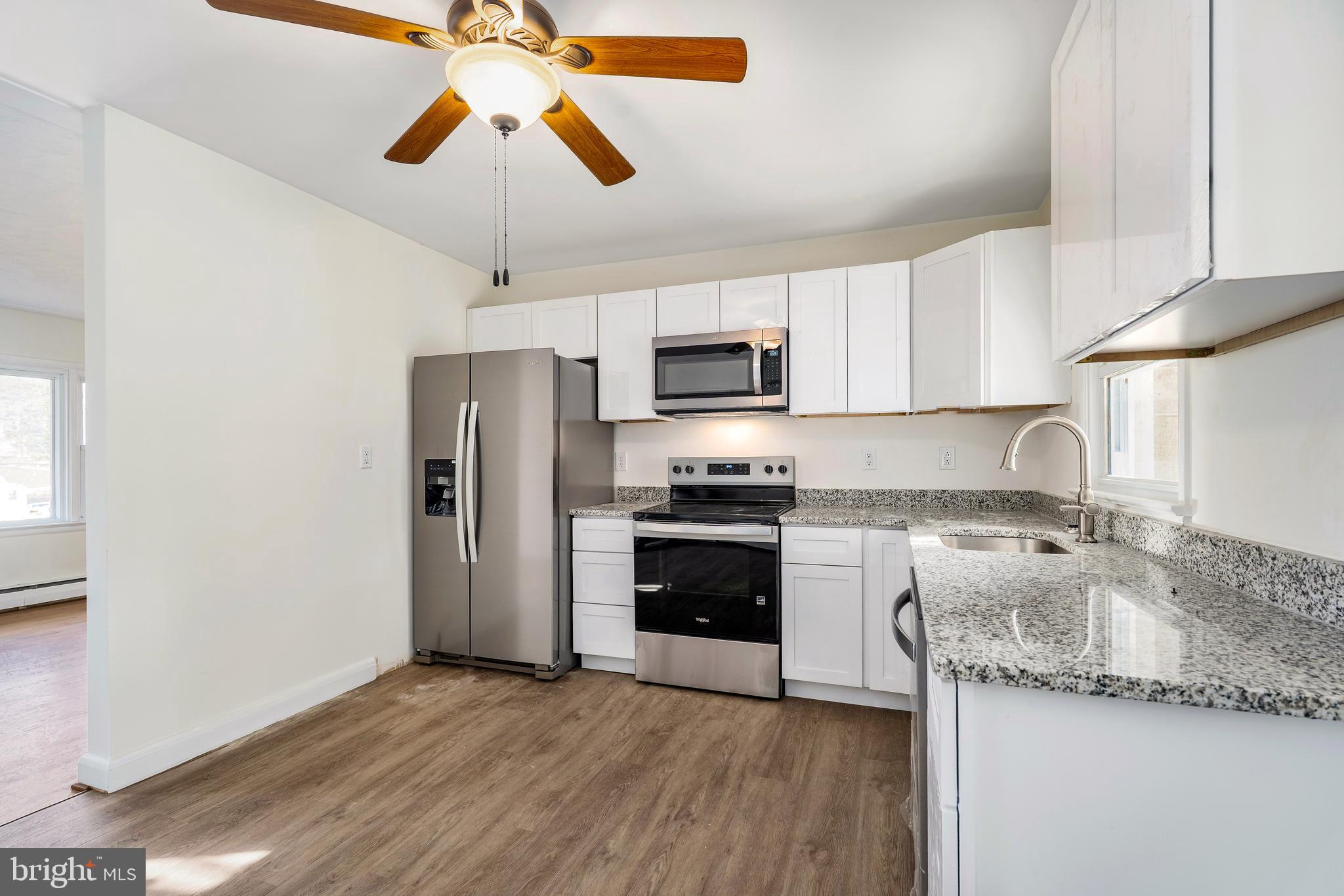 404 West Pearl Street Rising Sun, MD 21911 - Photo 8 of 23 a kitchen with granite countertop a refrigerator a stove a microwave a sink and dishwasher with wooden floor