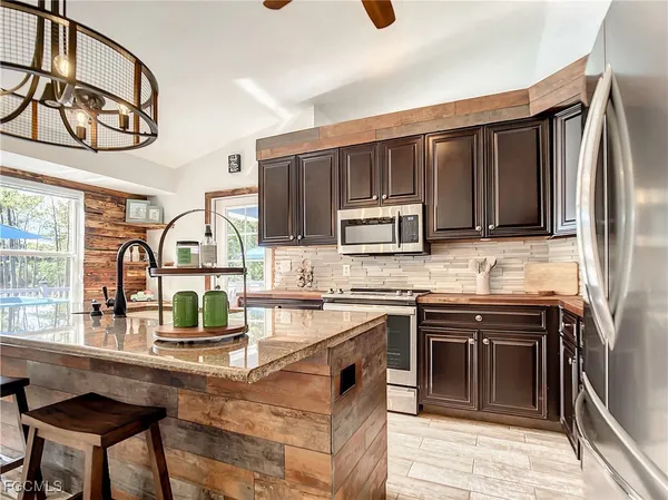 a kitchen with stainless steel appliances granite countertop a stove top oven a sink dishwasher a dining table and chairs with wooden floor