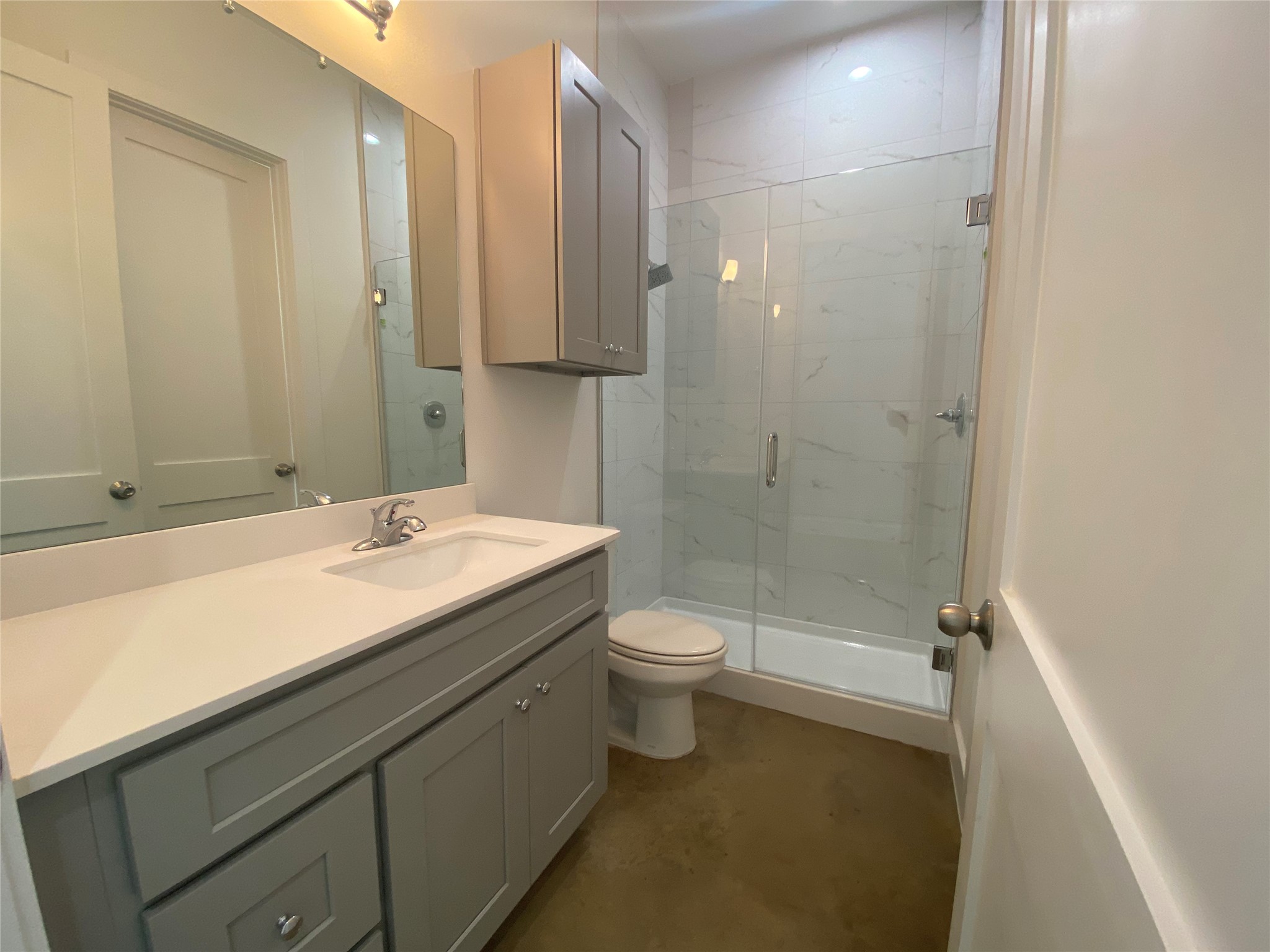 1916 Webberville Road, Unit B Austin, TX 78721 - Photo 12 of 25 Bathroom featuring a single vanity with a white countertop and gray cabinetry, a built-in medicine cabinet, a frameless glass shower enclosure, and white tiled shower walls