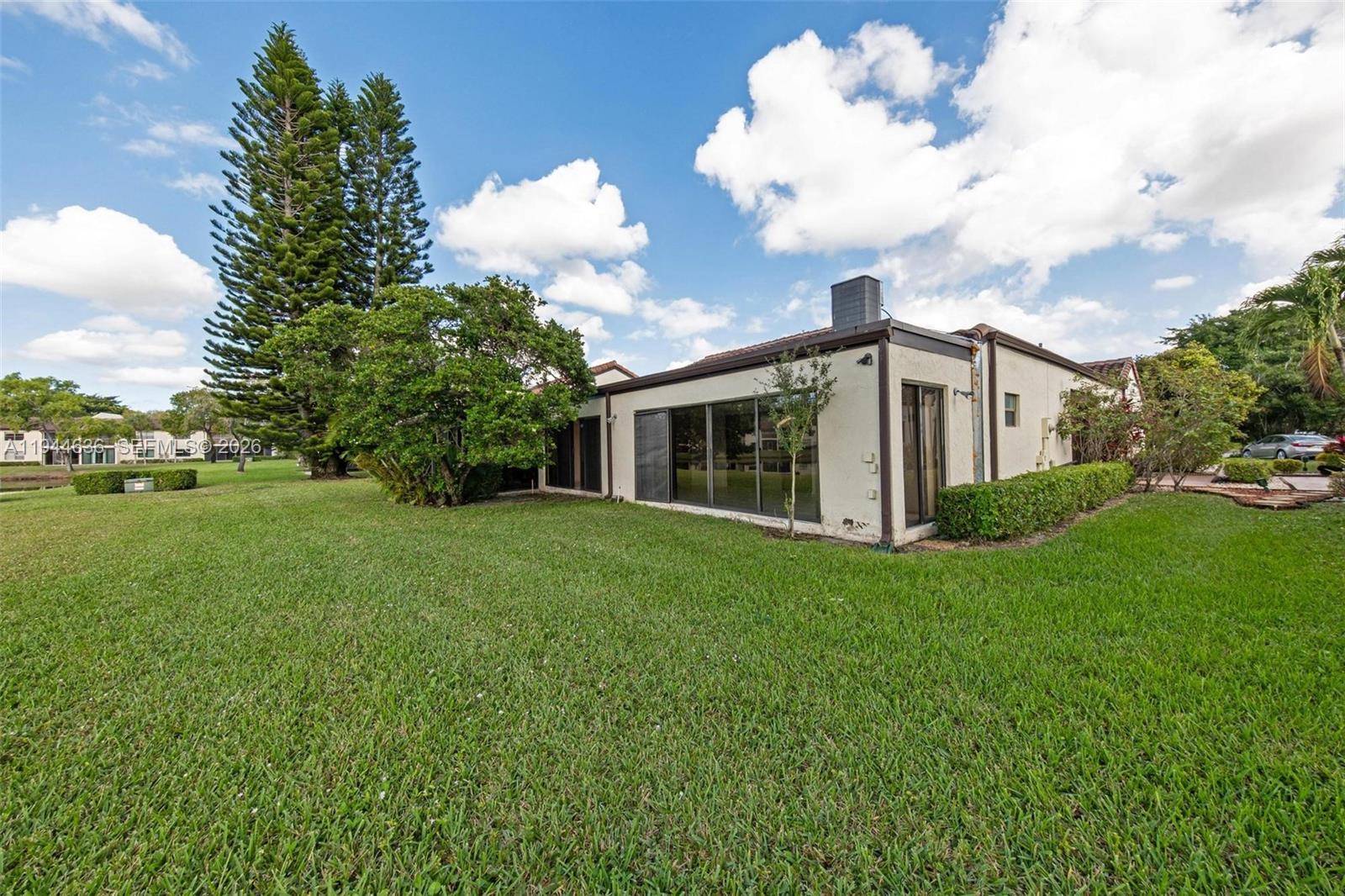 21877 Arriba Real Boca Raton, FL 33433 - Photo 35 of 40 a view of a white house next to a yard with big trees