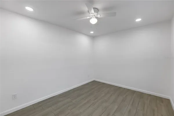 an empty room with wooden floor and fan