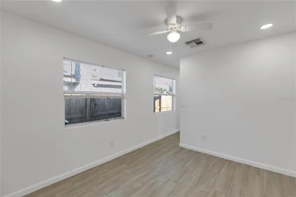 an empty room with wooden floor and windows