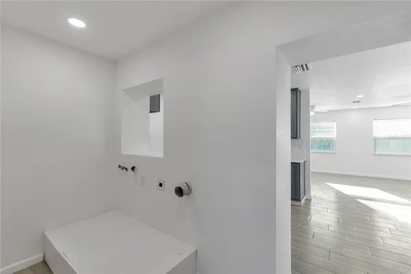 a view of a hallway with wooden floor and a bathroom