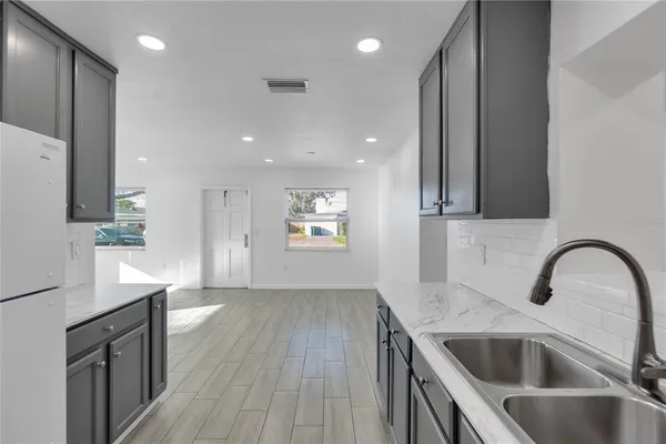 a kitchen with a sink dishwasher a refrigerator and a stove with wooden floor