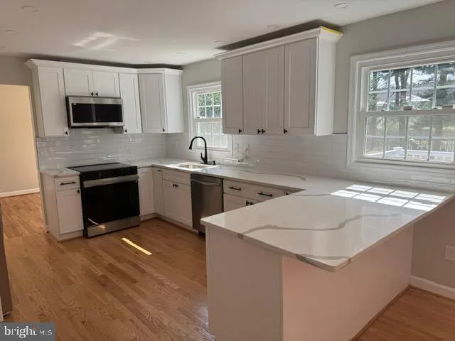 a kitchen with stainless steel appliances granite countertop a stove a sink and a microwave