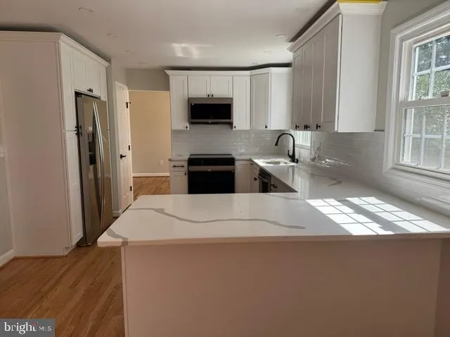 a kitchen with stainless steel appliances a refrigerator a sink a stove a microwave a sink and cabinets