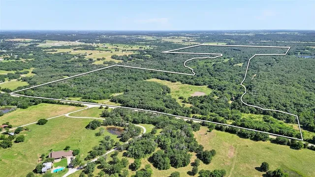 an aerial view of a residential houses with outdoor space and trees