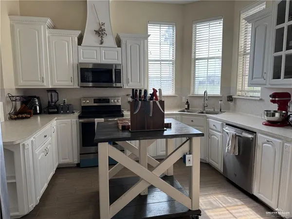 a kitchen with stainless steel appliances granite countertop a stove a sink and white cabinets