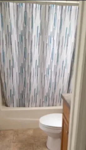 a bathroom with a toilet and a shower curtain