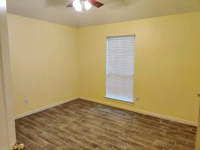 a view of empty room with window and wooden floor