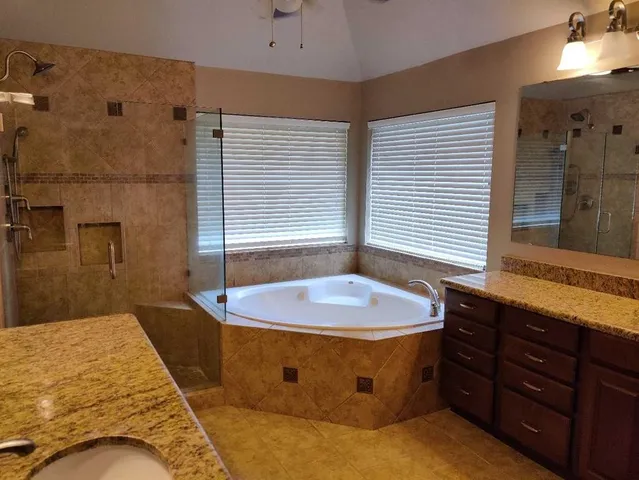 a spacious bathroom with a granite countertop tub sink and mirror