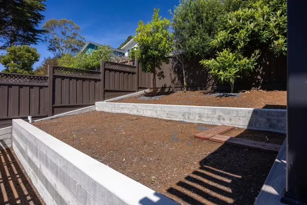 a view of a backyard with wooden fence and trees