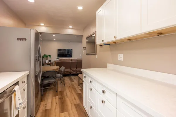 a view of a kitchen with kitchen island a sink wooden floor and living room view