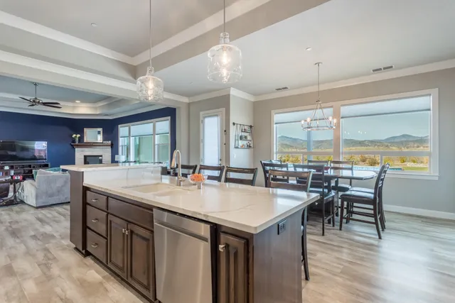 a kitchen with stainless steel appliances kitchen island granite countertop a stove top oven a sink a dining table and chairs