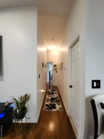 a view of a hallway to a livingroom with furniture and wooden floor
