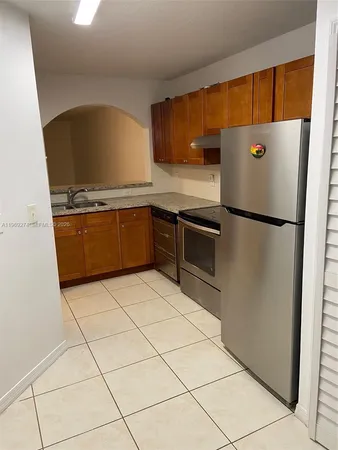 a kitchen with granite countertop a refrigerator and a stove top oven