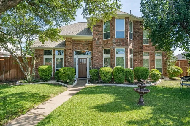 a view of a brick house with a yard and large trees