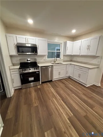 a kitchen with granite countertop a stove top oven a sink dishwasher and a refrigerator with wooden floor