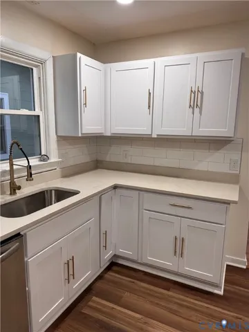 a kitchen with white cabinets and sink