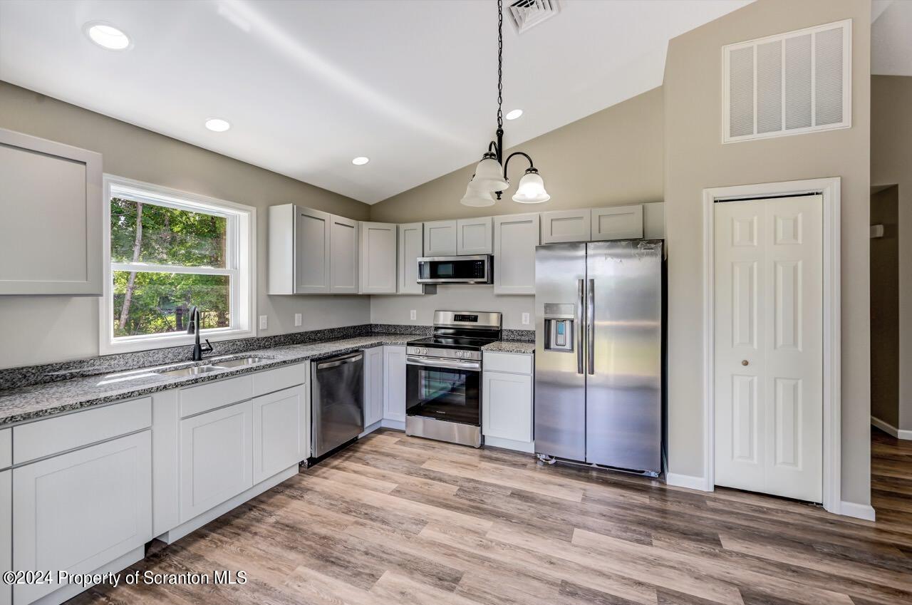 551 Back Street Scranton, PA 18504 - Photo 12 of 47 a kitchen with stainless steel appliances granite countertop a refrigerator a sink dishwasher a stove and white cabinets with wooden floor