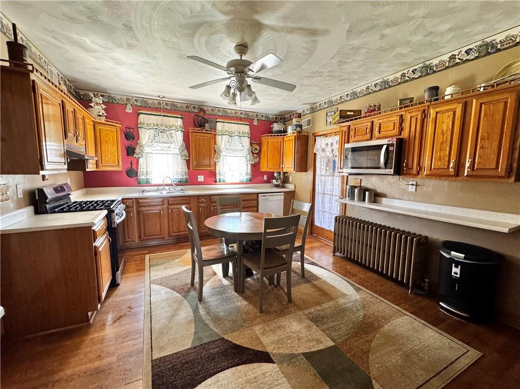 211 Stephens Street Vanderbilt, PA 15486 - Photo 7 of 48 a kitchen with stainless steel appliances granite countertop a stove a sink dishwasher a dining table and chairs with wooden floor
