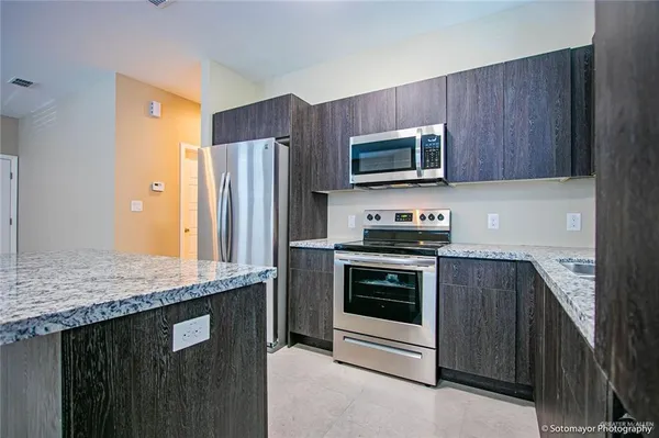 a kitchen with stainless steel appliances granite countertop a stove microwave and refrigerator