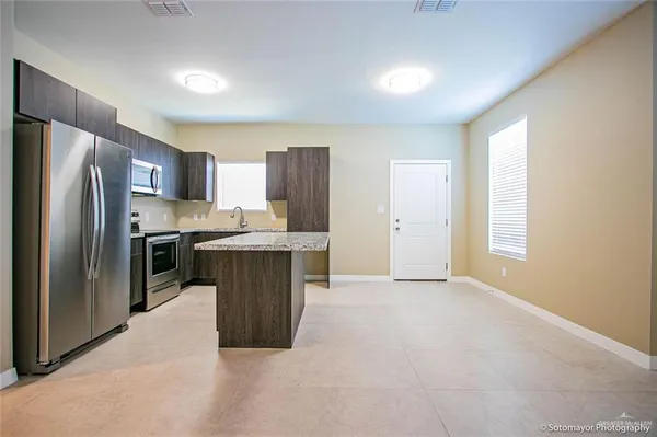 a kitchen with stainless steel appliances granite countertop a refrigerator a sink a stove a microwave and island