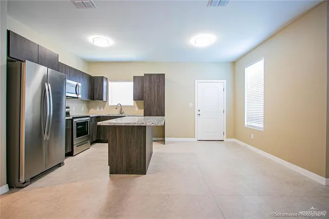 a kitchen with stainless steel appliances granite countertop a refrigerator a sink a stove a microwave and island