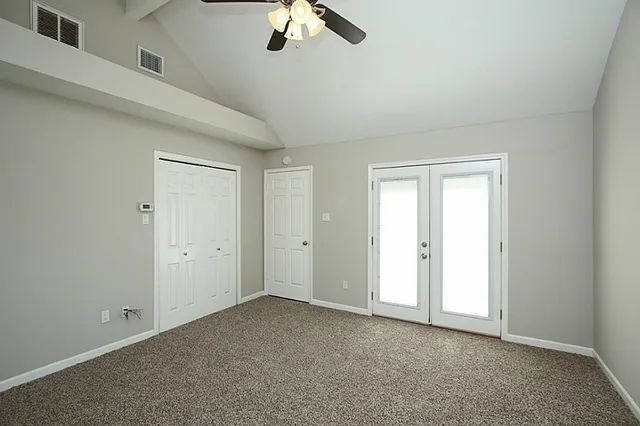 an empty room with a ceiling fan and window