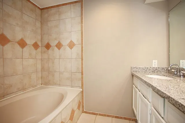 a bathroom with a granite countertop sink and a bathtub