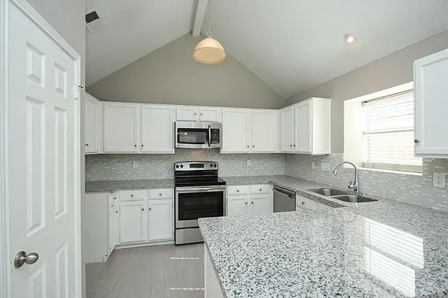 a kitchen with stainless steel appliances granite countertop a sink a stove a refrigerator and cabinets