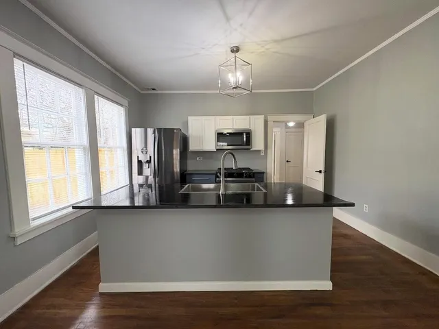 a kitchen with stainless steel appliances granite countertop a sink a microwave a refrigerator and a stove