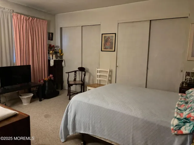 a bedroom with a bed and a flat tv screen on the dresser