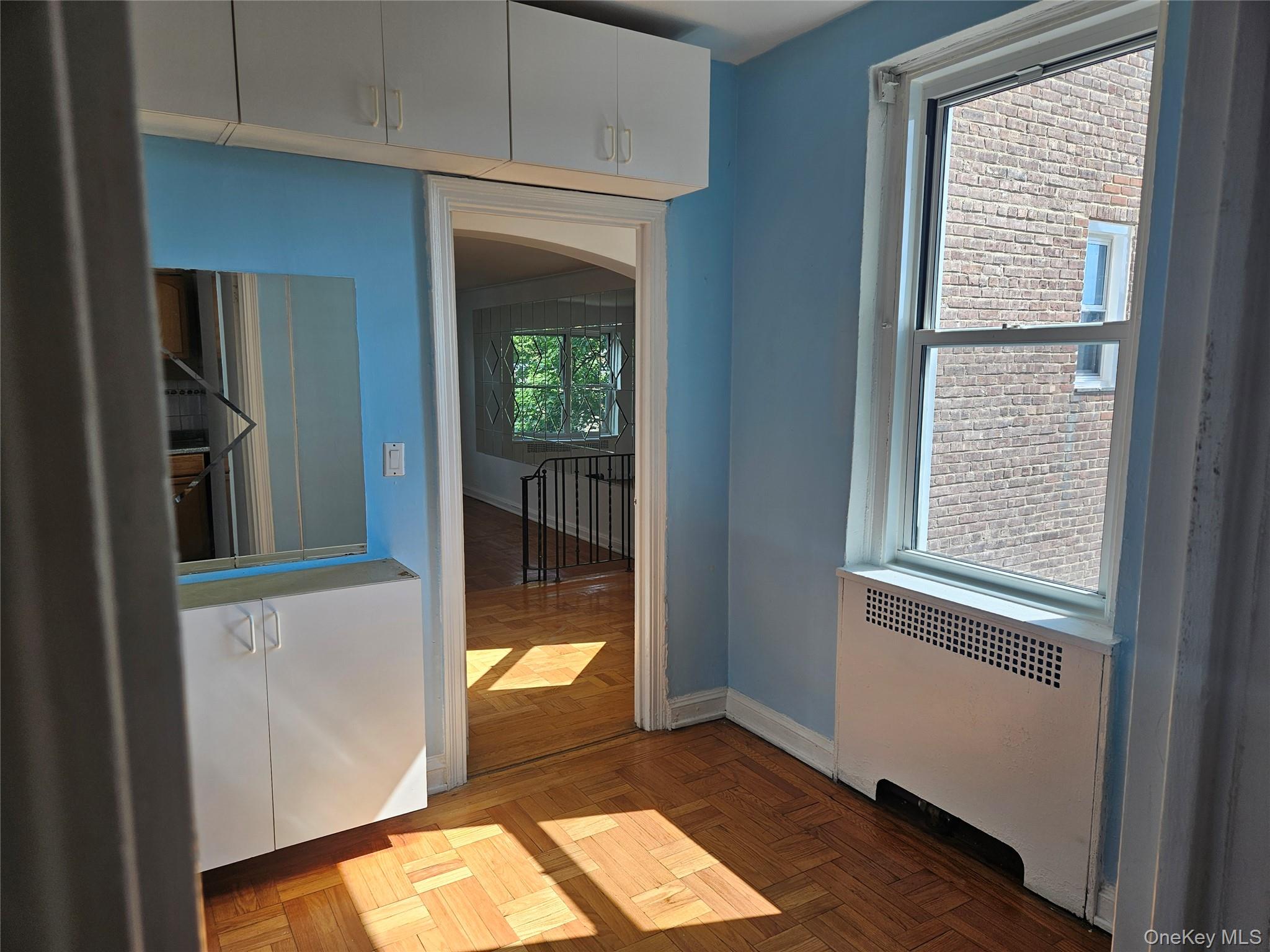 72-15 37th Avenue, Unit 3H Queens, NY 11372 - Photo 6 of 14 Empty room with radiator and arched walkways