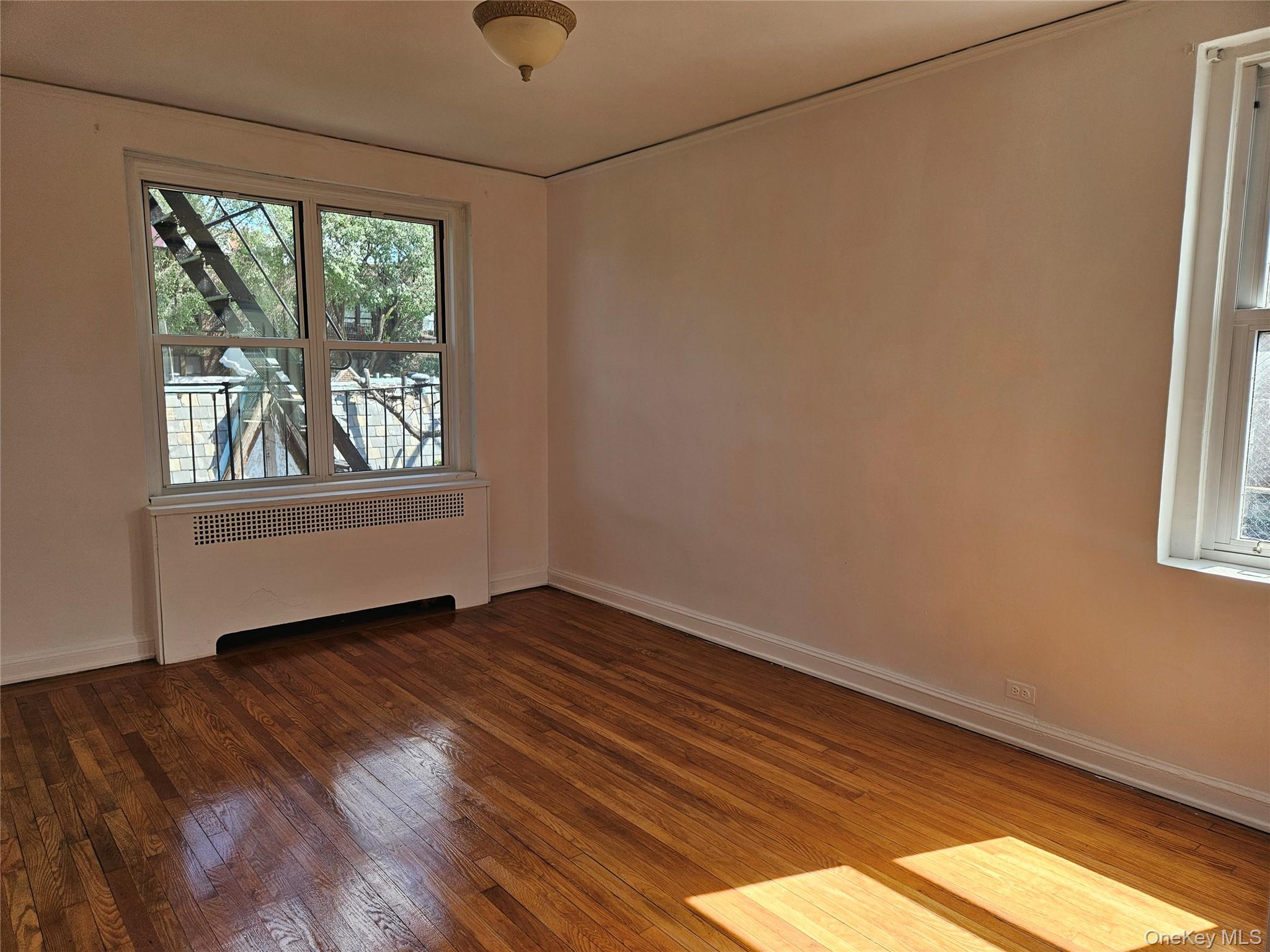 72-15 37th Avenue, Unit 3H Queens, NY 11372 - Photo 8 of 14 Spare room with radiator and wood finished floors