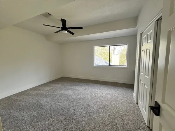 an empty room with windows and ceiling fan