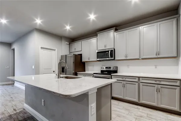 a kitchen with stainless steel appliances a sink a stove a microwave a center island and a window