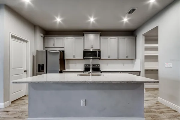 a kitchen with kitchen island a refrigerator and a stove top oven