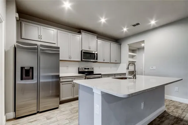 a kitchen with stainless steel appliances granite countertop a refrigerator a sink a stove a microwave and wooden cabinets