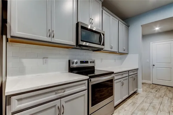 a kitchen with stainless steel appliances granite countertop white cabinets and a stove a oven with wooden floor