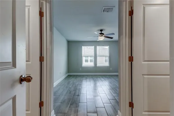 a view of a hallway with wooden floor and a bathroom