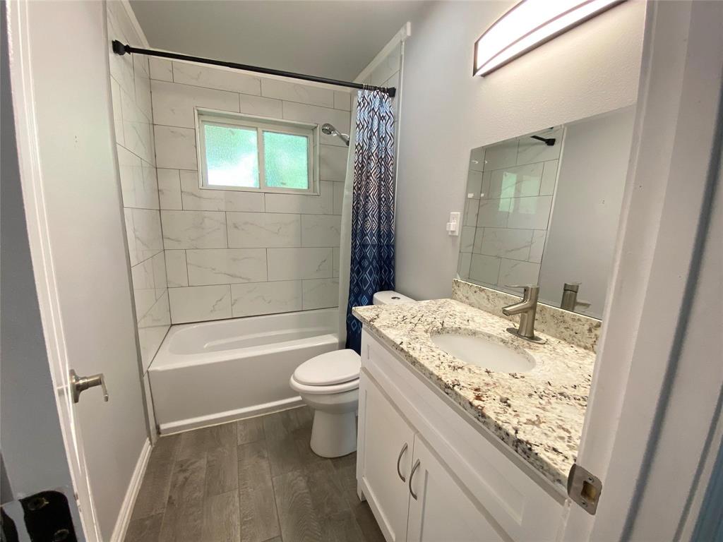 3130 Hillglenn Road Dallas, TX 75228 - Photo 9 of 10 Bathroom featuring a white vanity with a granite countertop and undermount sink, a large mirror, and a wall-mounted light fixture