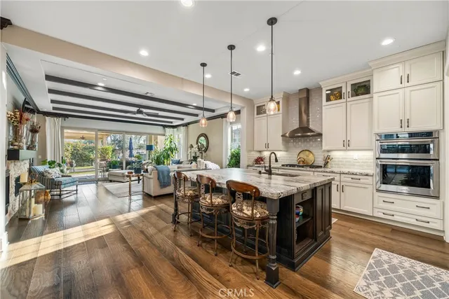 a kitchen with stainless steel appliances granite countertop a stove and a view of living room