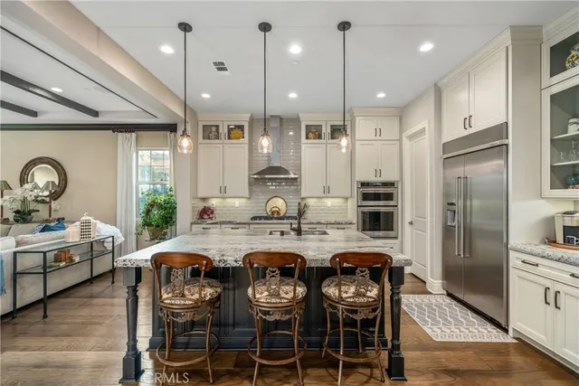 a kitchen with kitchen island granite countertop a stove a refrigerator and a dining table with wooden floor