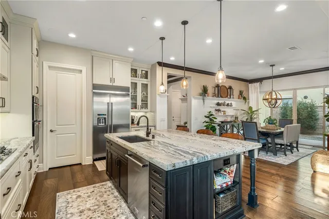 a kitchen with granite countertop a stove a refrigerator a oven and a dining table with wooden floor