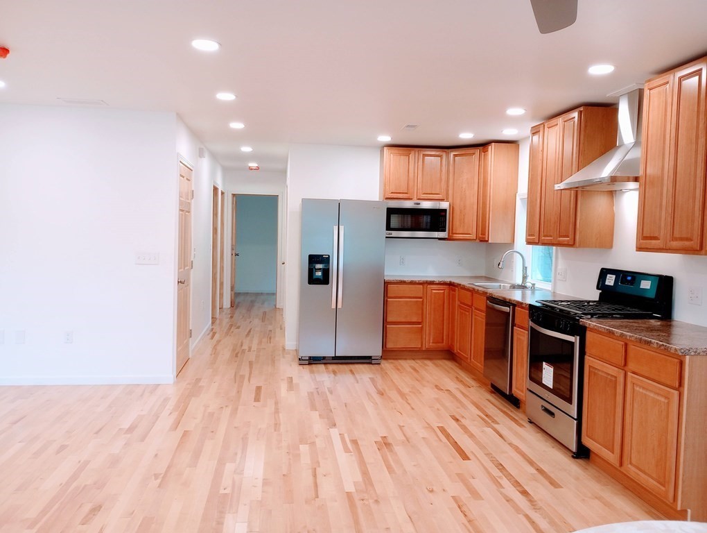 98 Gatewood Road Springfield, MA 01119 - Photo 4 of 21 a large kitchen with stainless steel appliances granite countertop a large stove a refrigerator a sink and dishwasher with wooden floor