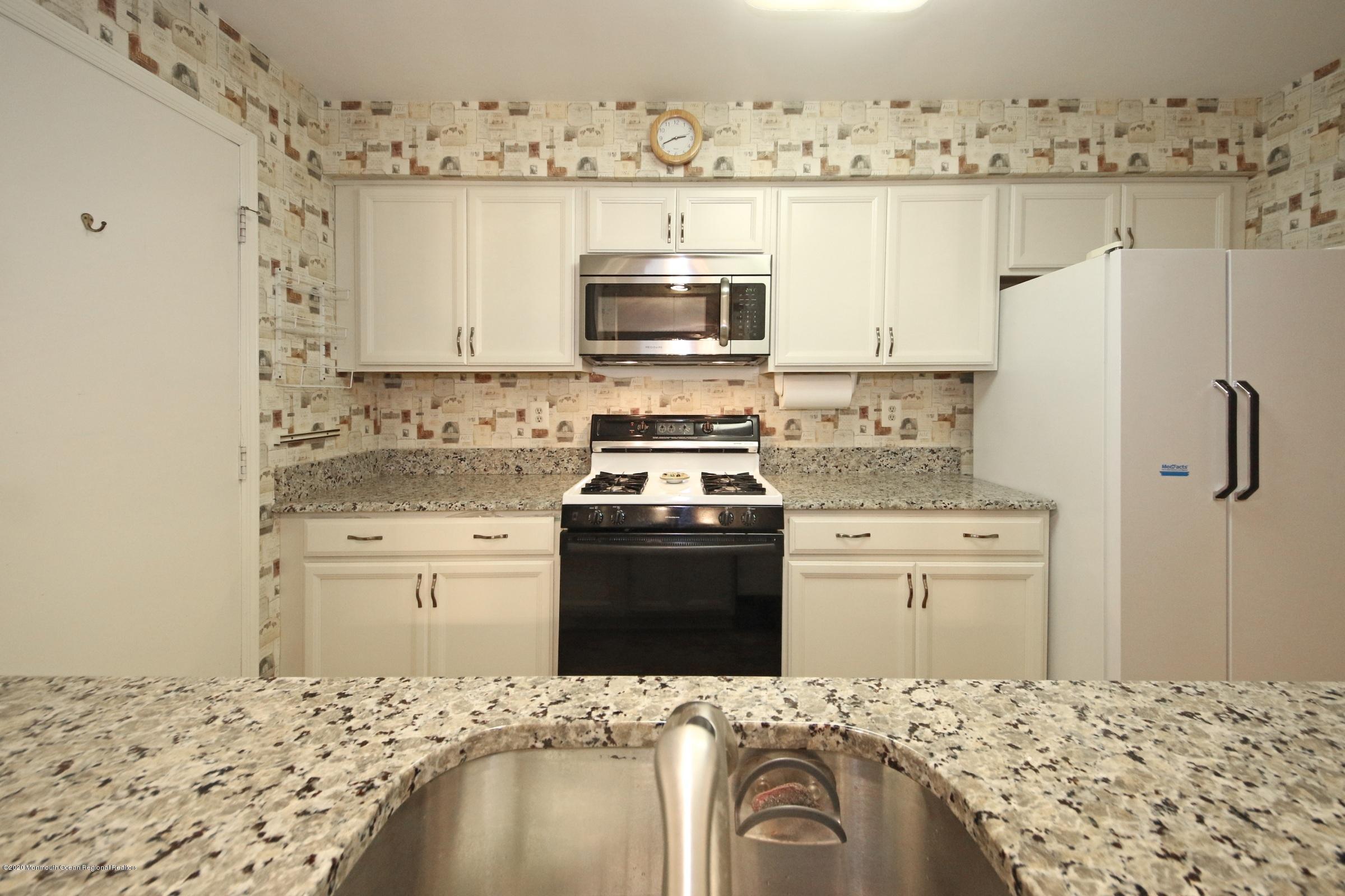 5 Racquet Road Wall, NJ 07719 - Photo 6 of 22 a kitchen with granite countertop white cabinets and stainless steel appliances